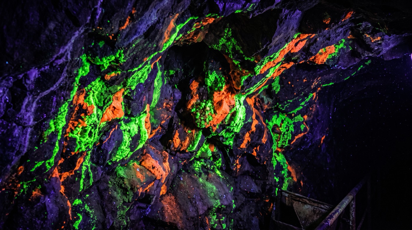 Rocks glowing neon green and orange under ultraviolet light inside the Sterling Hill Mining Museum